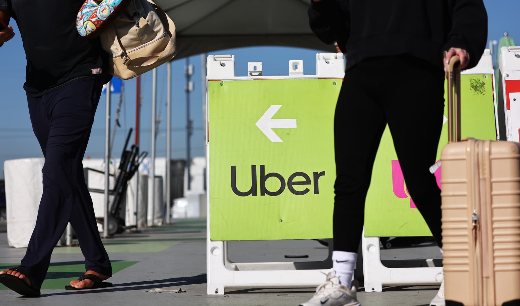 Travelers walk past a sign pointing toward the Uber ride-share vehicle pickup area at Los Angeles International Airport in Los Angeles on Feb. 8, 2023.